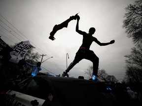 A demonstrator jumps off a police cruiser during a protest after police allegedly shot and killed a man, who local media report is identified by the victim's mother as Daunte Wright, in Brooklyn Center, Minnesota, U.S., April 11, 2021.