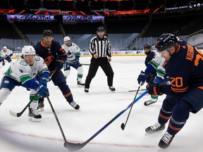 Slater Koekkoek (20) of the Edmonton Oilers battles for the puck against Brock Boeser (6) of the Vancouver Canucks at Rogers Place on May 15, 2021 in Edmonton.