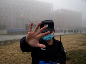 In this Feb. 3, 2021, file photo, a security person moves journalists away from the Wuhan Institute of Virology after a World Health Organization team arrived for a field visit.