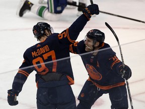 The Edmonton Oilers' Connor McDavid (97) celebrates his 100th point in 53 games with teammate Leon Draisaitl (29) against the Vancouver Canucks at Rogers Place in Edmonton on Saturday, May 8, 2021.