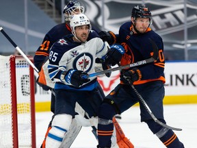 Edmonton Oilers’ Dmitry Kulikov (70) battles Winnipeg Jets’ Mathieu Perreault (85) during the second period of NHL North Division playoff action at Rogers Place in Edmonton, on Wednesday, May 19, 2021.
