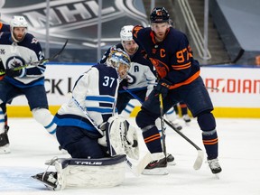 Edmonton Oilers’ Connor McDavid (97) watches Winnipeg Jets’ goaltender Connor Hellebuyck (37) make a save during the first period of Game 2 of their NHL North Division playoff series at Rogers Place in Edmonton, on Friday, May 21, 2021.