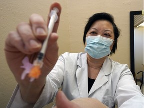 Pharmacist Joanna Wong administers a COVID-19 vaccine to a patient at Market Drugs Medical pharmacy in Edmonton on Tuesday, April 13, 2021.