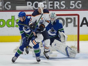 Vancouver Canucks goalie Thatcher Demko (35) looks on as Vancouver Canucks defenseman Nate Schmidt (88) checks Edmonton Oilers forward Jesse Puljujarvi (13) in the second period at Rogers Arena on May 4, 2021.