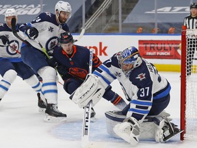 Winnipeg Jets goaltender Connor Hellebuyck (37) makes a save with Edmonton Oilers forward Kailer Yamamoto (56) looking for a rebound during the first period in game one of the first round of the 2021 Stanley Cup Playoffs at Rogers Place on May 19, 2021.