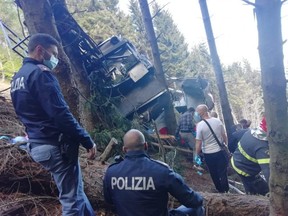Emergency workers surround the wreckage of a cable car that fell from the Stresa-Alpine-Mottarone line in Stresa, Italy, Sunday, May 23, 2021.