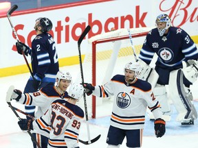 Edmonton Oilers forward Ryan Nugent-Hopkins (93) celebrates his second-period, power-play goal with Alex Chiasson (left) and Leon Draisaitl in Winnipeg on April 27, 2021.
