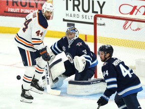 Winnipeg Jets goaltender Connor Hellebuyck tracks a shot with Edmonton Oilers forward Zach Kassian lurking in Game 3 of a Stanley Cup playoff series in Winnipeg on Sun., May 23, 2021.