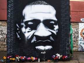 In this March 10, 2021, a woman walks near the makeshift memorial of George Floyd in Minneapolis, Minn.