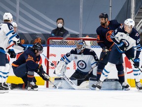 Winnipeg Jets goalie Connor Hellebuyck stops a shot by Edmonton Oilers forward James Neal, left, as Oilers forward Zack Kassian and Jets defenceman Logan Stanley, at right, look on during NHL playoff action on May 19, 2021, at Rogers Place.