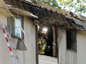 A firefighter looks for hot spots following a fire at an apartment building, 5620 118 Ave., in Edmonton, Sunday June 13, 2021.