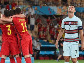 Portugal's forward Cristiano Ronaldo, right, reacts as Belgium's players celebrate their victory at the end of the UEFA EURO 2020 round of 16 football match between Belgium and Portugal at La Cartuja Stadium in Seville on June 27, 2021.