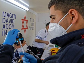 A paramedic with Israel's Magen David Adom medical services prepares a dose of the Pfizer-BioNTech COVID-19 vaccine to inoculate a Palestinian man in a mobile clinic on Feb. 26, 2021, at the Damascus Gate in Jerusalem's Old City.