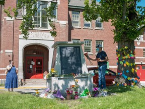 People lay flowers in front of the administration building at the former Kamloops Indian Residential School, after the remains of 215 children were found at the site in Kamloops, B.C., May 29, 2021.