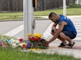 A man brings flowers and pays his respects at the scene where a man driving a pickup truck struck and killed four members of a Muslim family in London, Ont., June 7, 2021.