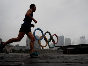 A jogger runs past a newly installed Olympic rings for celebrating the 2020 Tokyo Olympic Games in Yokohama, Japan, June 30, 2021.