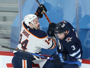 Edmonton Oilers forward Devin Shore (left) leans into Winnipeg Jets defenceman Tucker Poolman in Winnipeg on April 27, 2021.