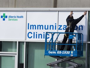 James Yanick puts up signage for the rapid flow-thru COVID-19 vaccination site at the Edmonton Expo Centre.