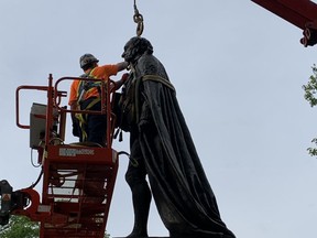 Work crews remove a statue of Canada's first prime minister Sir John A. Macdonald from City Park in downtown Kingston, Ont., where it has stood since 1895, on Friday, June 18, 2021.