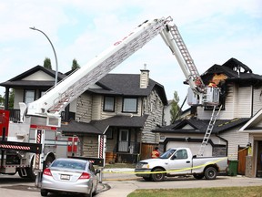 Investigators probe the scene of a house fire on Oakmere Close in Chestermere, AB east of Calgary on Friday, July 2, 2021. Jim Wells/Postmedia