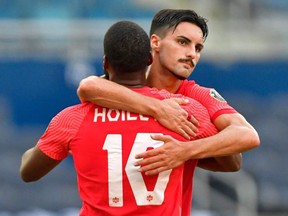 Canada's forward Junior Hoilett (L) is hugged by teammate Canada's midfielder Stephen Eustaquio after Hoilett scored a penalty kick against Haiti during their CONCACAF Gold Cup match on July 15, 2021 at Children's Mercy Park in Kansas City, Kansas.