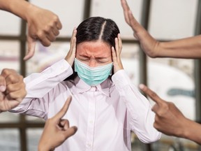 Asian woman was sick with high fever wearing hygienic mask are bullied and hate surrounded by hands mocking her, scoffing in the outbreak situation of Coronavirus 2019 infection or Covid-19