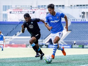 Paris Gee (No. 2) of FC Edmonton plays the ball away from Alex Marshall of HFX Wanderers FC in CPL play at Investors Group Field in Winnipeg, Man, on July 10, 2021.