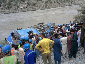 Rescue workers and onlookers gather around a wreck after a bus plunged into a ravine following a bomb explosion in Kohistan district of Khyber Pakhtunkhwa province on July 14, 2021.