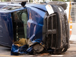 A Ram pickup is seen tipped on its side after being smashed in a crash caused by a woman who allegedly stole a water truck and caused a multi-vehicle crash on Jasper Avenue at 109 Street in Edmonton, on Friday, July 30, 2021.