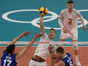 Canada's Lucas van Berkel spikes the ball past the Italian defence during their preliminary round pool A match between at the 2020 Summer Olympics, Saturday, July 24, 2021, in Tokyo, Japan.