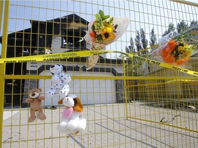 Flowers and stuffed animals were left outside the scene of a fatal house fire in Chestermere where 7 people died Friday.