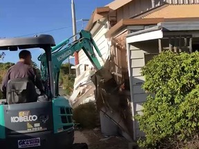In this screengrab from video, one of the Taylor brothers uses an excavator to damage their late mother's home.