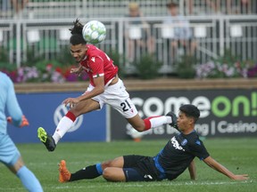 Cavalry FC Mo Farsi (C) gets a shot away over Edmonton FC defender Paris Gee in this file photo from Calgary's  Atco Field on August 3, 2021.