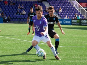 Marco Bustos of Pacific FC, front, tries to fend off Hunter Gorskie of FC Edmonton at Starlight Stadium in Victoria, B.C., on Aug. 7, 2021.