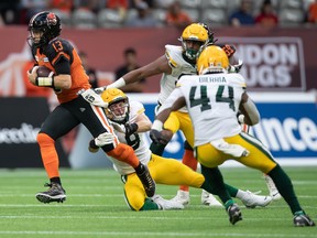 B.C. Lions quarterback Michael Reilly (13) gets away from Edmonton Elks defensive end Mathieu Betts (9) and rushes for a first down in Vancouver on Thursday, Aug. 19, 2021.