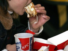 A woman eats a chicken burger in a KFC outlet.