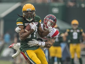 Derel Walker (87) of the Edmonton Elks is hauled down by Tre Watson (33) of the Montreal Alouettes at Commonwealth Stadium in Edmonton on Aug. 14, 2021.
