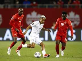 Andy Najar (No. 17) of Honduras dribbles the ball as Atiba Hutchinson (No. 13) and Alphonso Davies (No. 19) of Canada defend during a 2022 World Cup Qualifying match at BMO Field on September 2, 2021 in Toronto.