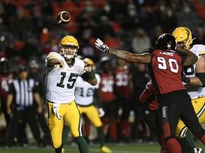 Edmonton Elks quarterback Taylor Cornelius (15) throws the ball past the arm of Ottawa Redblacks defensive lineman Cleyon Laing (90) in Ottawa on Tuesday, Sept. 28, 2021.