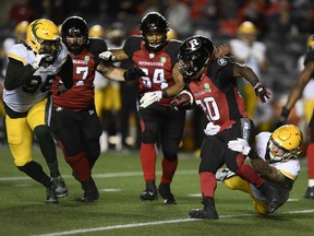 Ottawa Redblacks running back Timothy Flanders (20) tries to run past the tackle of Edmonton Elks defensive lineman Thomas Costigan (95) during first half CFL football action in Ottawa on Tuesday, Sept. 28, 2021.