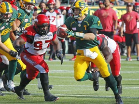 Edmonton Elks quarterback Trevor Harris (7) is chased by Calgary Stampeders defensive lineman Derek Wigan (97) at Commonwealth Stadium on Sept. 7, 2019.