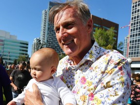 People’s Party of Canada leader Maxime Bernier poses with a baby and supporters during a rally at Central Memorial Park in downtown Calgary on Saturday, Sept. 18, 2021.