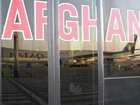 A Qatar Airways aircraft is reflected on the windowpanes of a shuttle bus carrying passengers to board the flight at the airport in Kabul on September 9, 2021.