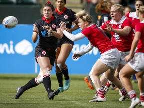 anada's Alysha Corrigan, front left, passes the ball as Britain's Megan Jones grabs her during a women's HSBC Canada Sevens rugby match in Edmonton on Sept. 25, 2021.