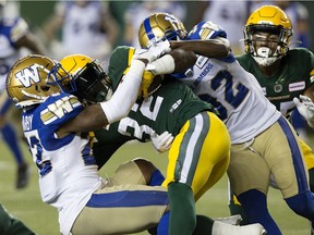 The Edmonton Elks' James Wilder Jr. (32) is tackled by the Winnipeg Blue Bombers' Alden Darby (22) and Deatrick Nichols (32) during first half CFL action at Commonwealth Stadium, in Edmonton Saturday Sept. 18, 2021. Photo by David Bloom