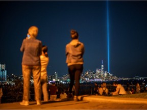 People watch the Tribute in Light art installation and the One World Trade Center on the day marking the 20th anniversary of the Sept. 11, 2001 attacks in New York City, as it is seen from Weehawken, New Jersey, on Sept. 11, 2021.