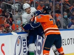 Edmonton Oilers’ Colton Sceviour (70) hits Vancouver Canucks’ Madison Bowey (4) during the first period of preseason NHL action at Rogers Place in Edmonton, on Thursday, Oct. 7, 2021.