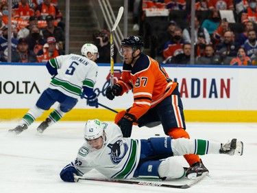 Edmonton Oilers captain Connor McDavid (97) takes down Vancouver Canucks’ Quinn Hughes (43) at Rogers Place in Edmonton on Wednesday, Oct. 13, 2021.