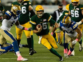 Edmonton Elks quarterback Taylor Cornelius (15) runs the ball past Winnipeg Blue Bombers defensive end Willie Jefferson (5) and Jackson Jeffcoat (94) at Commonwealth Stadium in Edmonton on Oct. 15.