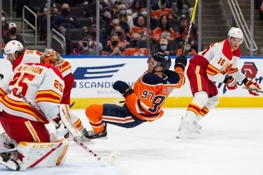 Edmonton Oilers' Connor McDavid (97) collides with Calgary Flames' goaltender Jacob Markstrom (25) while scoring a goal during third period preseason NHL action at Rogers Place in Edmonton, on Monday, Oct. 4, 2021.